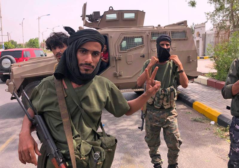 Fighters of the UAE-trained Security Belt Force, dominated by backers of the the Southern Transitional Council (STC) which seeks independence for south Yemen, pose for a picture while standing before an armoured vehicle in Khor Maksar in the centre of Yemen's second city of Aden on August 12, 2019. The head of Yemen's separatist movement said he was ready to take part in Saudi-brokered peace talks after clashes with pro-government forces killed dozens in the port city. Southern Transitional Council (STC) leader Aidarus al-Zubaidi had said late on August 11 that he was committed to a ceasefire in Aden, where the separatists have seized the presidential palace and army camps. / AFP / Nabil HASAN
