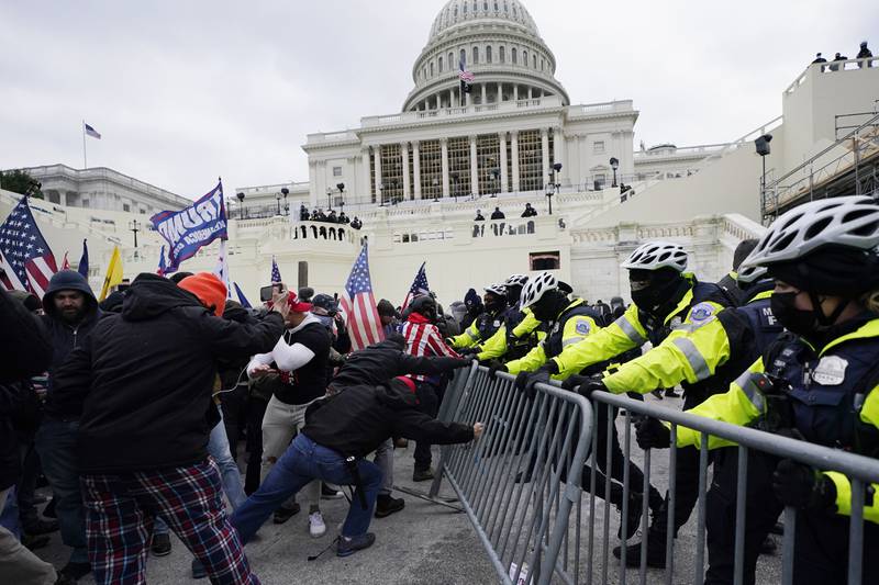 A mob loyal to Mr Trump tries to break through a police barrier at the Capitol. AP