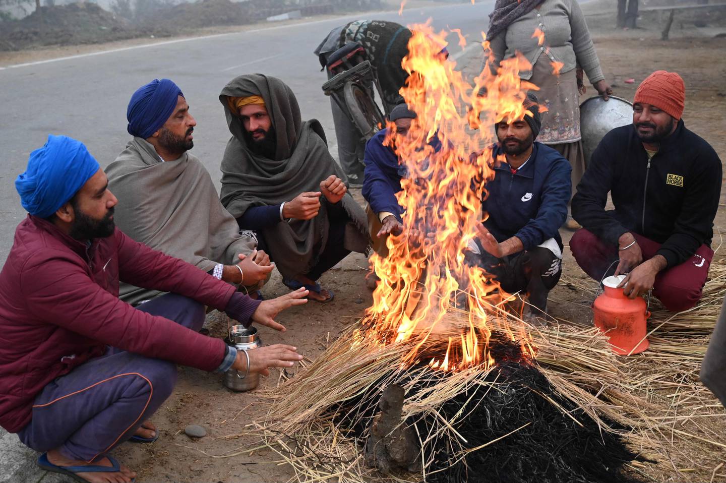Villagers sit around a fire on a foggy winter day on the outskirts of Amritsar on Monday. AFP