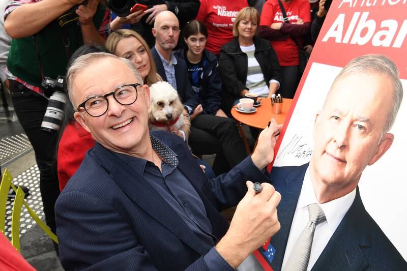 Australia's Prime Minister-elect Anthony Albanese signs a poster for a young boy as he shares a coffee near his home in Sydney. The Labor leader will be sworn in as Australia's 31st prime minister on Monday following his victory over Scott Morrison in the federal election. Getty Images