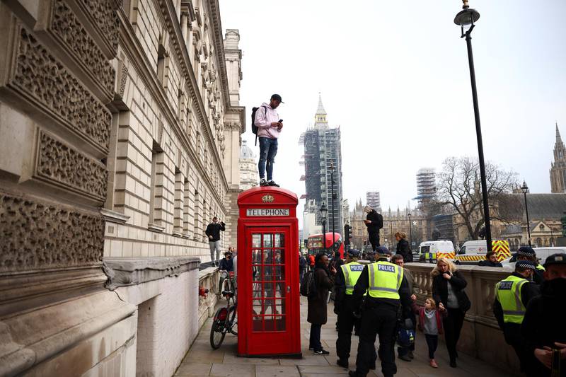 A man stands on a telephone booth during an anti-lockdown demonstration amid the coronavirus disease (COVID-19) outbreak in London.  Reuters