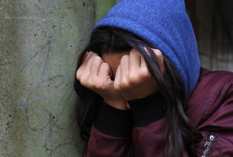 A teenage girl with her head in her hands. PA