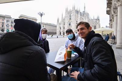 People sit at a cafe's terrace in central Milan, Italy. AFP