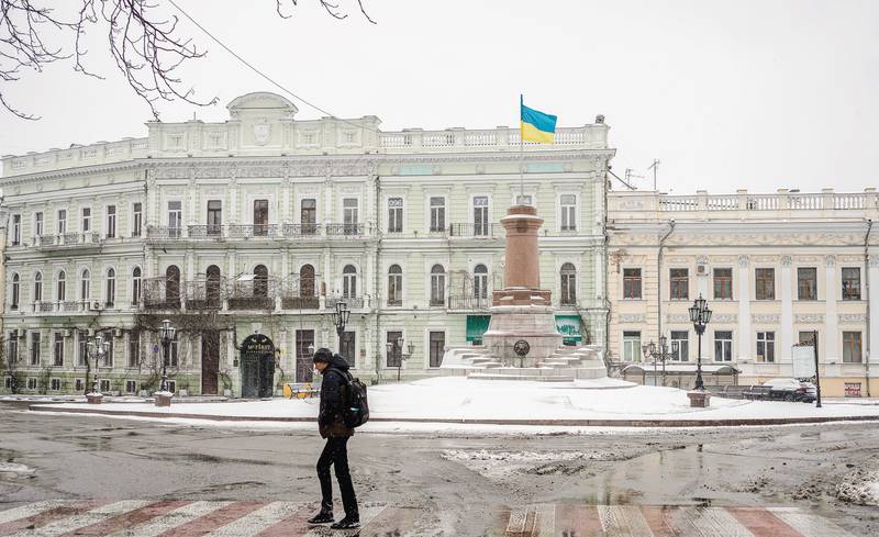 A citizen crosses a street in Odesa as a Ukrainian flag flies. Getty 