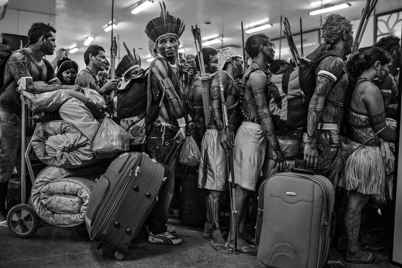 This image provided by World Press Photo, part of a series titled Amazonian Dystopia, by Lalo de Almeida for Folha de Sao Paulo/Panos Pictures which won the World Press Photo Long-Term Project award,, shows Members of the Munduruku community line up to board a plane at Altamira Airport, in Para, Brazil, on 14 June 2013.  After protesting at the site of the construction of the Belo Monte Dam on the Xingu River, they traveled to the national capital Brasilia to present their demands to the government.  The Munduruku community inhabit the banks of another tributary of the Amazon, the Tapajos River, several hundred kilometers away, where the government has plans to build further hydroelectric projects.  Despite pressure from indigenous people, environmentalists and non-governmental organizations, the Belo Monte project was built and completed in 2019.  (Lalo de Almeida for Folha de Sao Paulo / Panos Pictures / World Press Photo via AP)