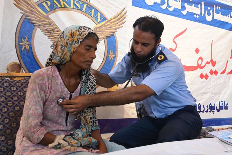 A Pakistan Air Force doctor examines a patient displaced by the floods at a makeshift medical camp in Rajanpur District, Punjab Province. AFP