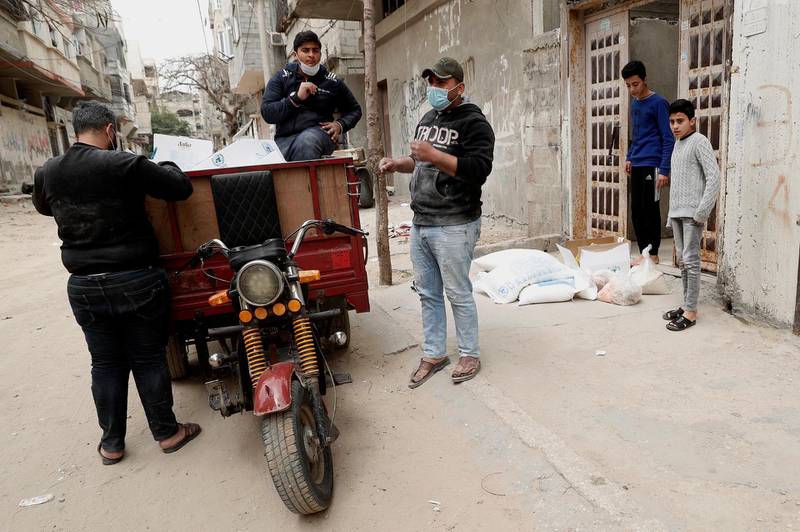 Palestinian workers distribute food supplies from the United Nations Relief and Works Agency (UNRWA) to a house, in the Sheikh Redwan neighbourhood of Gaza City.  AP