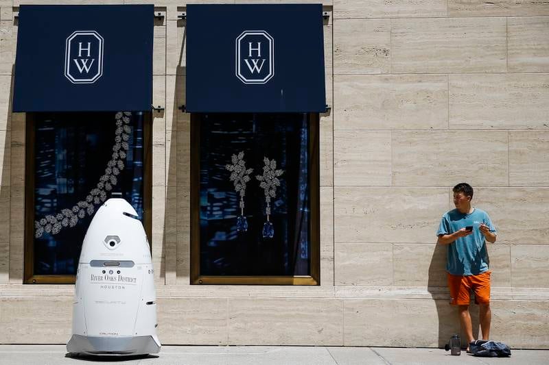 FILE - In this Friday, Aug. 18, 2017, file photo, a new security robot, nicknamed ROD2, drives toward Daniel Webb as it patrols the sidewalks and parking garage at River Oaks District in Houston. The robot recently became the latest addition to a patrol team eager to experiment with fast-evolving technology. According to a survey by the Pew Research Center, three-quarters of Americans say it is at least �������somewhat realistic������� that robots and computers will eventually perform most of the jobs currently done by people. Roughly the same proportion worry that such an outcome will have negative consequences, such as worsening inequality. (Michael Ciaglo/Houston Chronicle via AP, File)