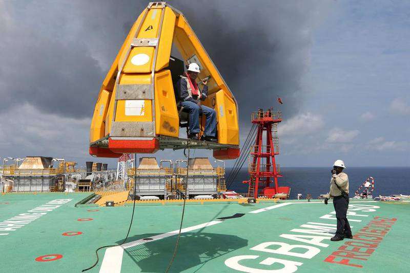 An oil worker is transferred via a ‘Frog’ basket from the tugboat Bourbon Auroch, operated by Bourbon SA, onto the deck of the Agbami floating production, storage and offloading vessel. George Osodi / Bloomberg