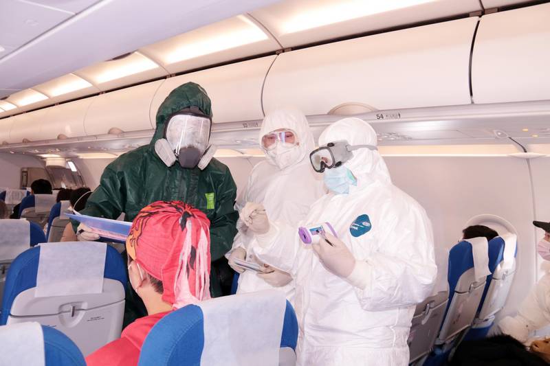 Medical personnel take temperature tests of passengers on board a plane at the airport in Zhoushan City, Zhejiang province, China.  EPA