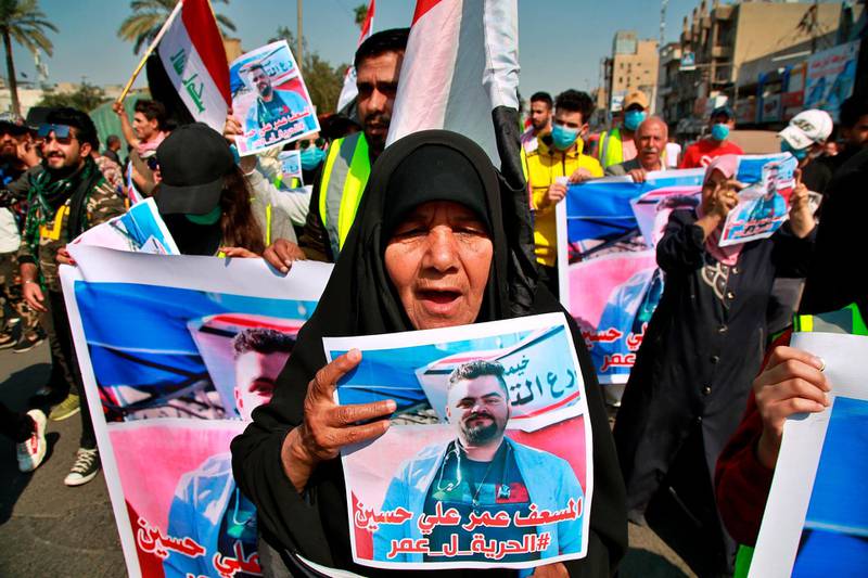 A woman holds a picture of her a missing protester son during ongoing anti-government protests, in Baghdad, Iraq, Sunday, February 23, 2020. Arabic on the poster reads, "Freedom for paramedic Omr Ali." AP Photo