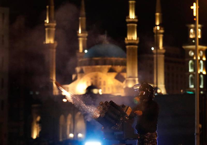 A riot police officer fires tear gas from a launcher against anti-government protesters trying to enter parliament square in downtown Beirut. AP