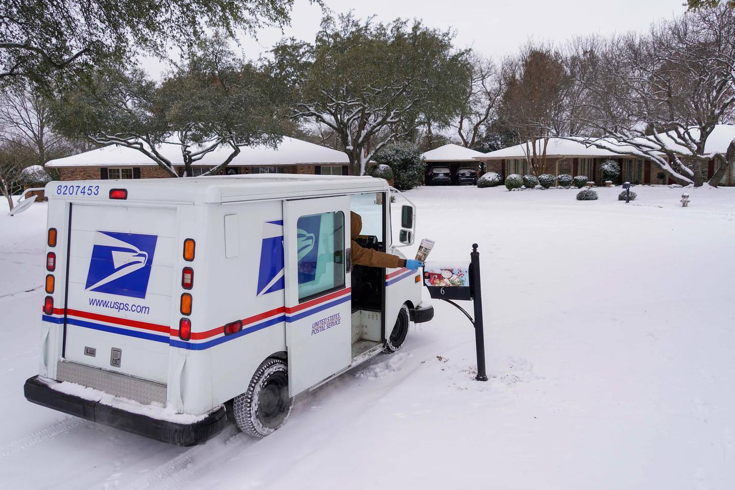 Letter carrier Angel Garcia delivers mail to a snow covered neighborhood after a second winter storm brought more snow and continued freezing temperatures to North Texas on Wednesday, Feb. 17, 2021, in Richardson, Texas. "We're going slow, but we are getting it delivered," Garcia said of USPS mail deliveries. (Smiley N. Pool/The Dallas Morning News via AP)