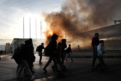 Students, on their way to school, cross a road through the smoke from burning tires which were set on fire by the anti-government protesters to block the southern entrance of a highway during a protest against the newly formed cabinet, in Beirut, Lebanon. AP Photo