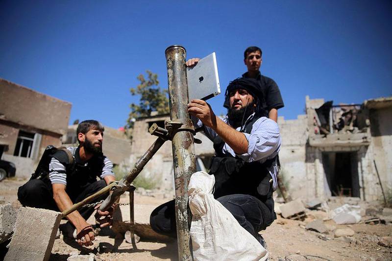 A member of the 'Ansar Dimachk' Brigade, part of the 'Asood Allah' Brigade which operates under the Free Syrian Army, uses an iPad during preparations to fire a homemade mortar at one of the battlefronts in Jobar, Damascus, Syria. Mohamed Abdullah / Reuters