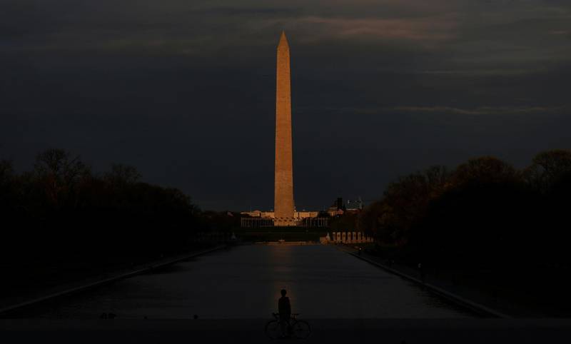 A cyclist stops in front of the Lincoln Memorial Reflecting Pool, with the Washington Monument lit by the setting sun at rear, as the spread of the coronavirus disease continues in Washington, US. Reuters