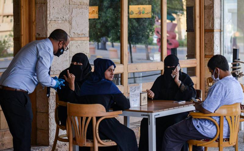 A mask-clad waiter takes orders from clients at a cafe in Saudi Arabia's capital Riyadh.   AFP
