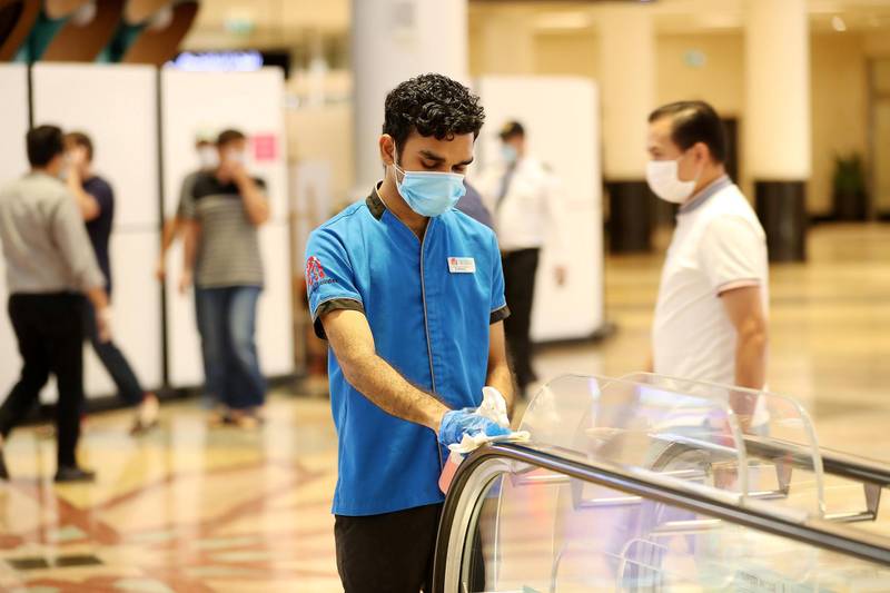 DUBAI, UNITED ARAB EMIRATES , April 29 – 2020 :- Cleaning staff  wearing protective face mask and gloves to prevent the spread of the coronavirus and sanitising the escalators railing  at Mall of the Emirates in Dubai. Authorities ease the restriction for the residents in Dubai. At present mall opening timing is 12:00 pm to 10:00 pm. Carrefour timing is 9:00 am to 10:00 pm. (Pawan Singh / The National) For News/Standalone/Online. Story by Patrick