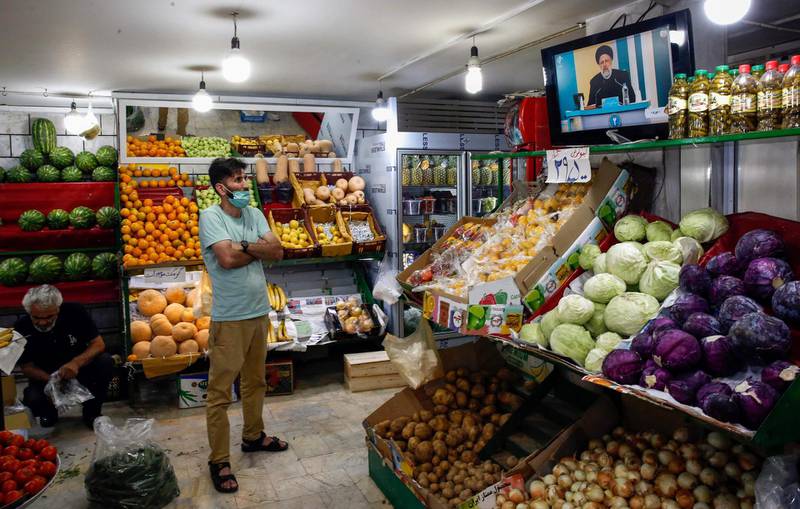 An Iranian man watches candidate Ebrahim Raisi speaking during the first televised debate between presidential candidates, at a fresh produce shop in the capital Tehran, on June 5, 2021. AFP