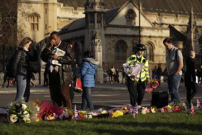A police officer places flowers beside floral tributes to victims of Wednesday's attack outside the Houses of Parliament in London. Matt Dunham / AP Photo