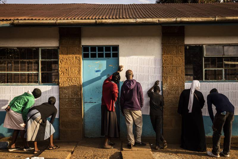 People look for their names on voting registers posted outside Kibera Primary School in Nairobi. Getty