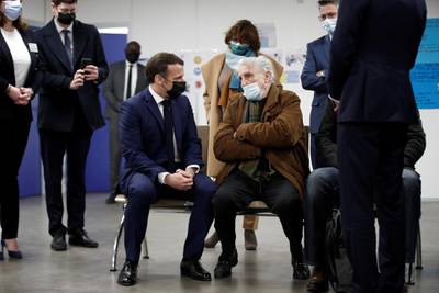 French President Emmanuel Macron talks with a patient as he visits a vaccination center at the Caisse Primaire d'Assurance Maladie in Bobigny, outside Paris, France. AP Photo