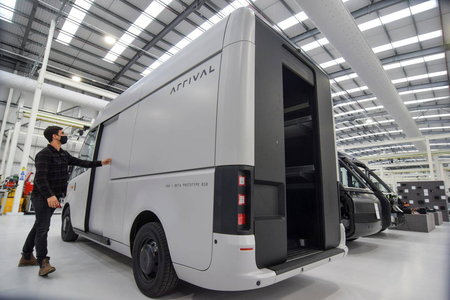 A man looks at a fully-electric test van, due to go into production in 2022, built by electric van and bus maker Arrival Ltd, that has seen a spike in interest due to soaring e-commerce amid the coronavirus disease (COVID-19) pandemic and looming fossil-fuel vehicle bans, in Banbury, Britain, February 23, 2021. Picture taken February 23, 2021. REUTERS/Nick Carey