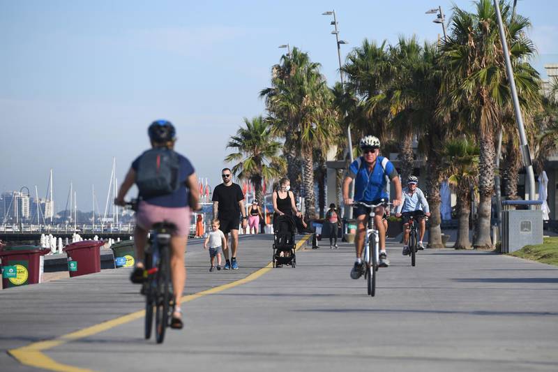 People walk and cycle at St. Kilda Beach in Melbourne, Australia, Wednesday, Feb. 17, 2021. Melbourne, Australia's second-largest city, will relax its third lockdown restrictions after authorities contained the spread of a COVID-19 cluster centered on hotel quarantine. (Erik Anderson/AAP Image via AP)