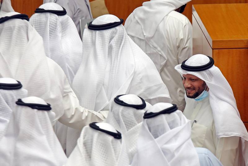 Kuwaiti Finance Minister Barrak al-Shaitan (R) greets colleagues during a parliament session at Kuwait's national assembly in Kuwait City on August 12, 2020. Kuwait's national assembly rejected a no-confidence motion against al-Shaitan with 32 members supporting him. He was opposed by 12 members while three lawmakers abstained. / AFP / YASSER AL-ZAYYAT
