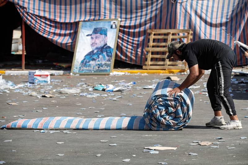 A supporter of Mr Al Sadr rolls up a mattress as their encampment in the Green Zone is dismantled. AFP