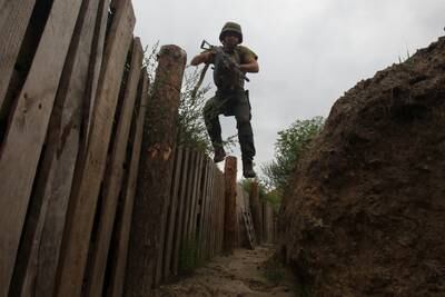 A member of the Ukrainian National Guard jumps into a trench at a position near a front line, in the Kharkiv region. Reuters