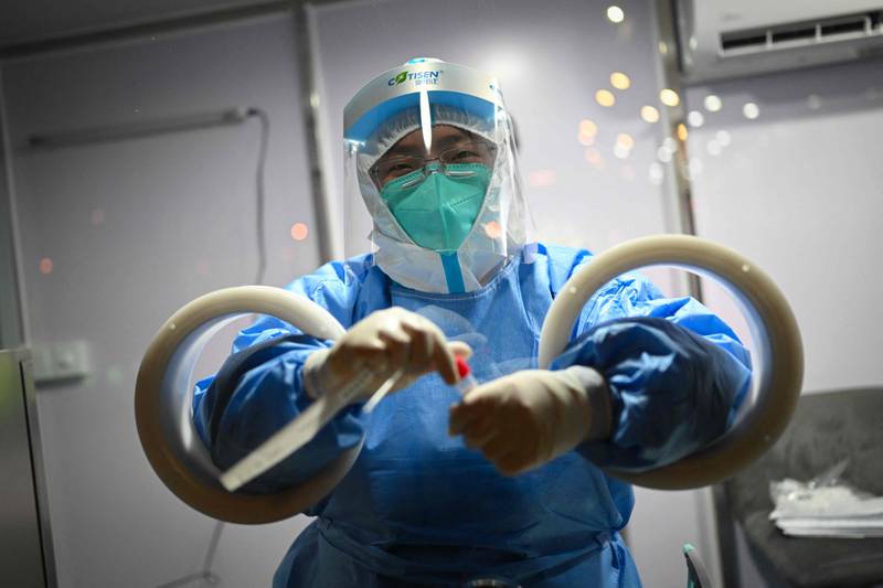 A health worker holds a swab sample collected from a member of the media before the start of the 2022 Winter Olympics in Beijing. AFP