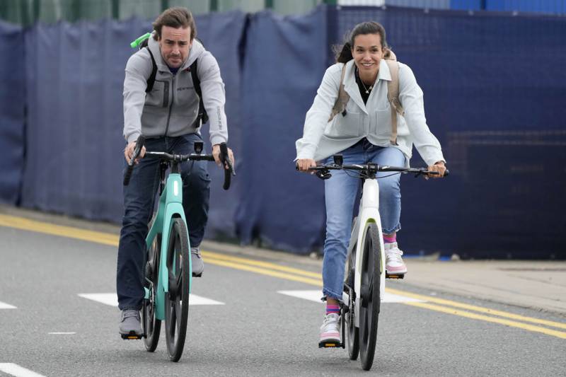Alpine driver Fernando Alonso, left, and partner Anbdrea Schlager arrive by bicycle. AP