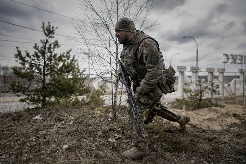A Ukrainian serviceman approaches vehicles in Irpin, on the outskirts of Kyiv. AP Photo / Vadim Ghirda