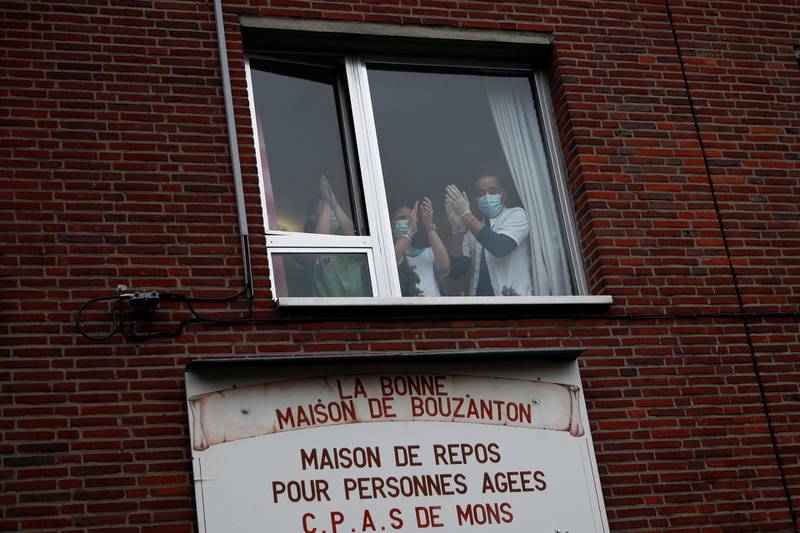 Staff members applaud as vials of the Covid-19 vaccine are delivered to the La Bonne Maison de Bouzanton care home in Mons, Belgium. Reuters