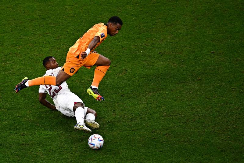 Qatar's Assim Madibo slides in on defender Jurrien Timber of the Netherlands. AFP