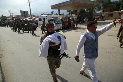 An Afghan security officer carries a baby after gunmen attacked a maternity hospital, in Kabul, Afghanistan. AP Photo