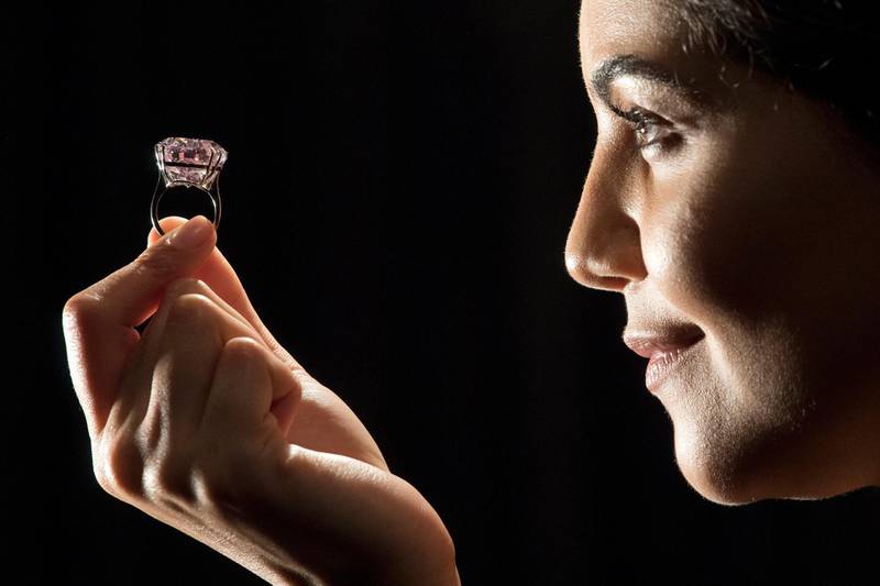 A model poses with a 59.60-carat oval mixed-cut pink diamond, known as "The Pink Star", during a photocall at Sotheby's auction house in London on March 20, 2017, to promote its forthcoming auction. - The diamond, with an estimated value of 48.5 million GBP (60 million euros; 60 million USD), is said to be the largest Internally Flawless Fancy Vivid Pink diamond that the Gemological Institute of America (GIA) has ever graded, and is set to be auctioned in Hong Kong on April 4, 2017. (Photo by Justin TALLIS / AFP)