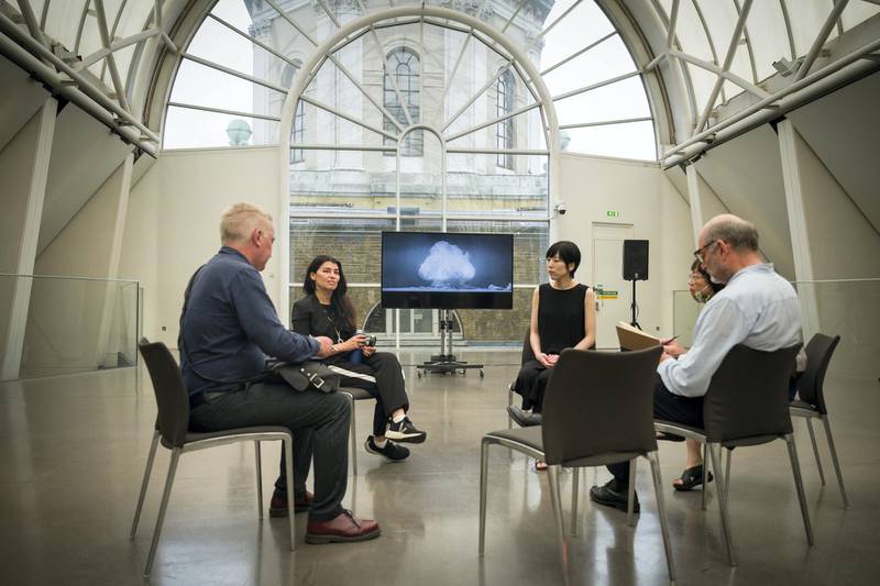 LONDON, ENGLAND - AUGUST 06: Artists Es Devlin (2L) and Machiko Weston (2R) are interviewed by journalists while a screen displays a part of their commissioned video installation "I Saw The World End", at the Imperial War Museum on August 06, 2020 in London, England. The film is made up of quotes from key figures in the story of the bombing of Hiroshima and Nagasaki, from the original concept of building a nuclear bomb through to those who experienced the blast first hand. Originally due to be broadcast on the screens of Piccadilly Circus 75 years to the minute since the bomb was dropped on Hiroshima, the screening was moved online due to the recent explosion in Beirut. (Photo by Leon Neal/Getty Images)