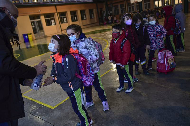 A group of young students wearing masks disinfect their hands before entering the Luis Amigo school after the Christmas holidays, in Pamplona, northern Spain. AP