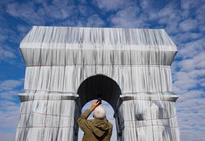 A visitor photographs the fully wrapped Arc de Triomphe monument. EPA