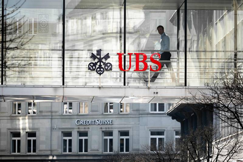 A employee is seen in silhouette next to a sign of Swiss giant banking UBS and a sign of Credit Suisse bank in Zurich. UBS's share price plunged on Monday following its $3.2bn deal to take over troubled Swiss rival Credit Suisse, but then regained some ground. AFP