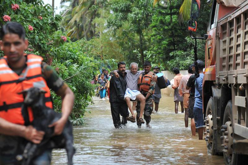 Rescue personnel carry animal and elderly people to safety from flood waters during a rescue operation in Mala village in Thrissur District, Kerala. AFP