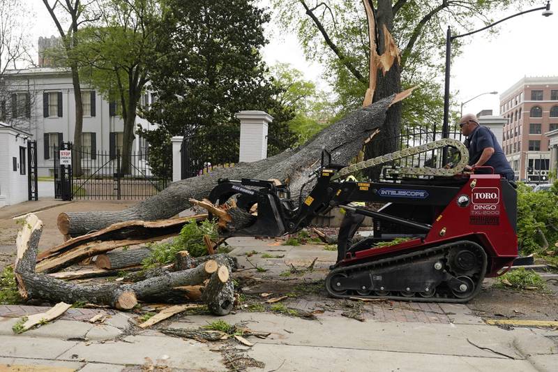 A state grounds engineer uses a mini skid steer to remove some of the limbs and trunk from this downed tree that was felled by strong winds on the grounds of the Mississippi Governor's Mansion on to a main intersection of central Jackson. AP