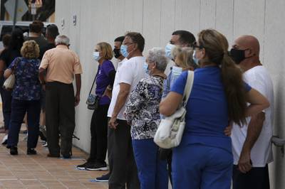Voters wearing protective masks stand in line to cast ballots at an early voting polling location for the 2020 Presidential election in Miami, Florida, U.S., on Monday, Oct. 19, 2020. The Biden campaign and its supporters have booked $15.4 million worth of media advertising on Oct. 19, compared with $6 million booked by the Trump campaign and its backers, according to data by ad-tracking firm Advertising Analytics. Photographer: Marco Bello/Bloomberg