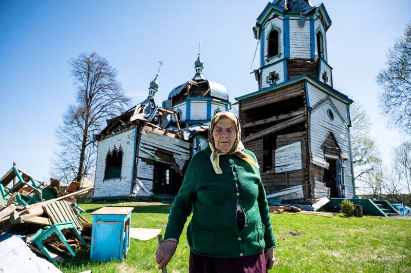 Lyubov, 85, stands in front of a 19th century wooden church, damaged by rocket attack, in the Zhytomyr region of Ukraine. Reuters