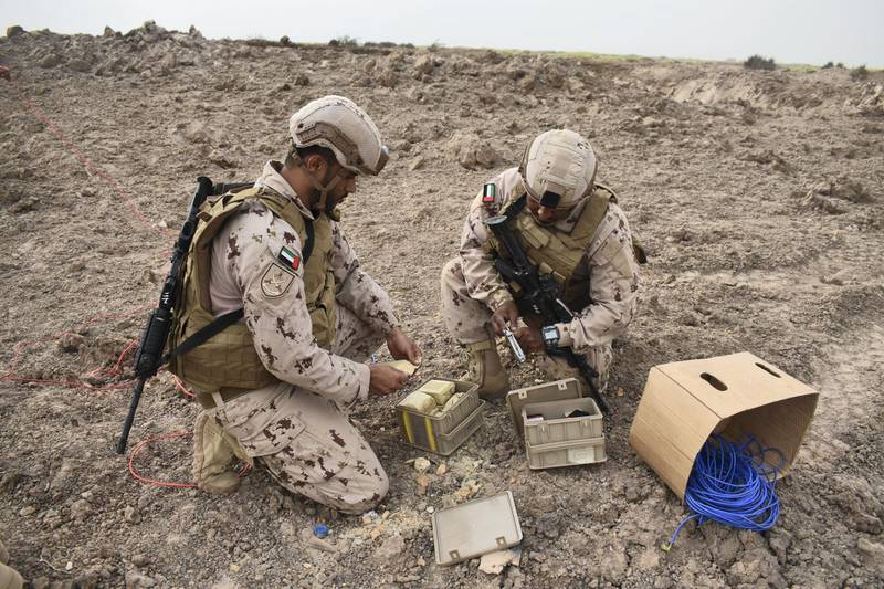 Two UAE soldiers unwrap plastic explosive, and detonator cord, as they prepare a Houthi landmine cache for controlled explosion. Gareth Browne / The National