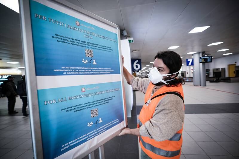 A worker at Caselle airport in Turin, Italy, sets up a sign informing travellers from China of mandatory Covid tests. EPA