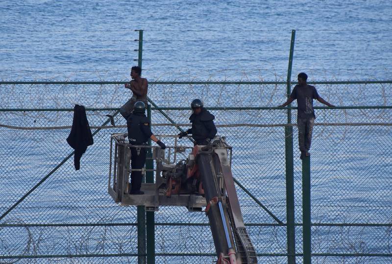 Spanish Civil Guard officers use a boom lift while African migrants sit on top of a border fence as  they attempt to cross into Spanish territories, between Morocco and Spain's north African enclave of Ceuta, Spain, August 30, 2019. REUTERS/Stringer  NO RESALES. NO ARCHIVES