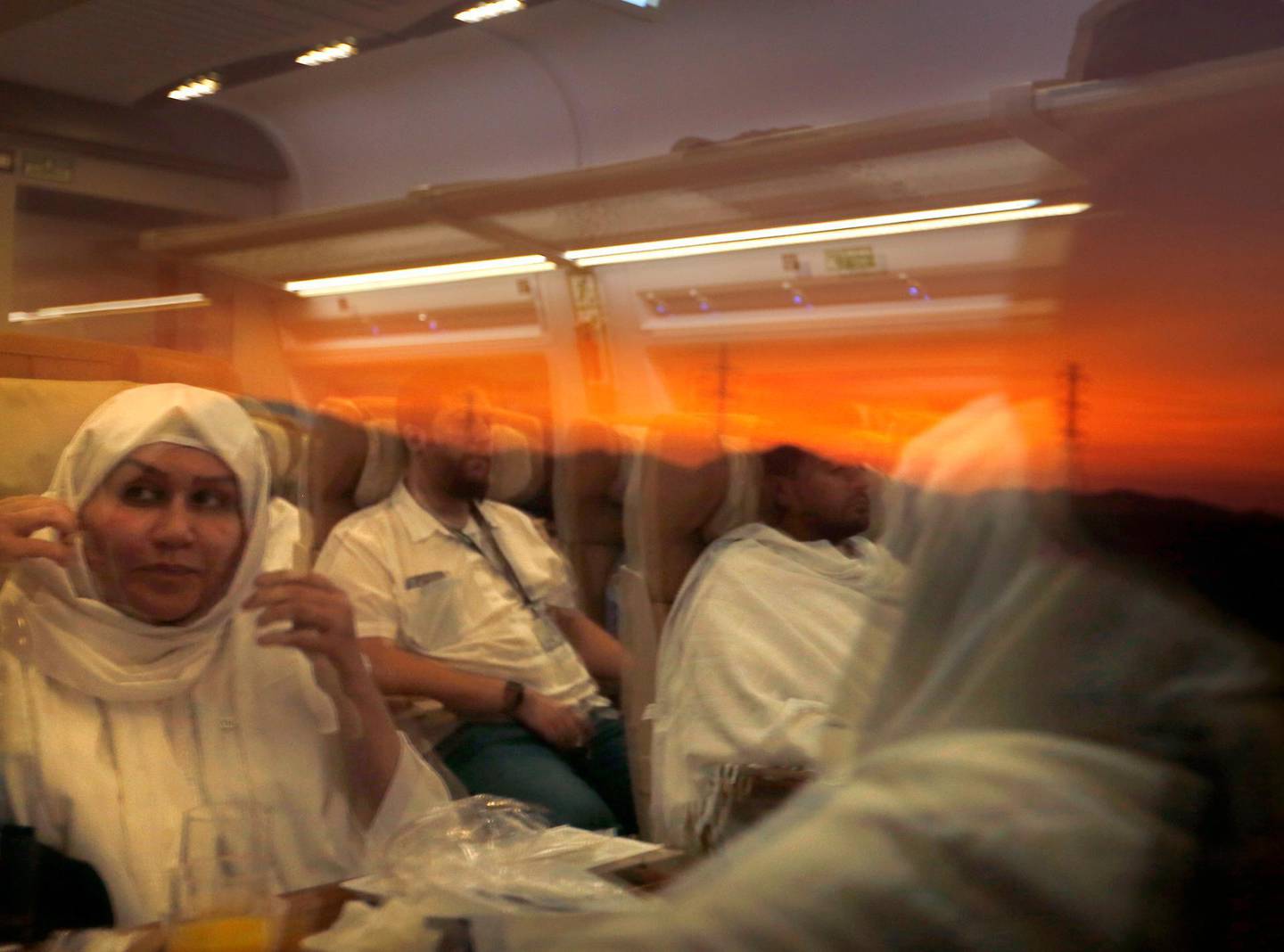 Pilgrims on their way to Mecca are reflected on the window of the Haramain High-Speed Railway train in the holy city of Medina, Saudi Arabia, Thursday, Aug. 8, 2019. Hundreds of thousands of Muslims have arrived in the kingdom to participate in the annual hajj pilgrimage, which starts Friday, a ritual required of all able-bodied Muslims at least once in their life. (AP Photo/Amr Nabil)